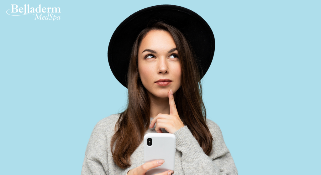 Young woman holding cell phone, thinking about preventative Botox